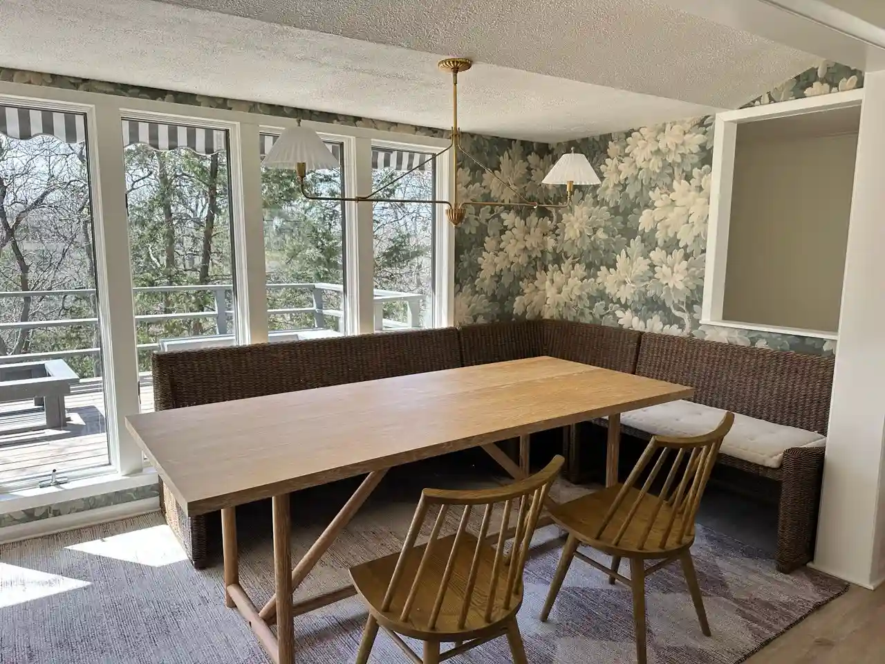 A dining nook with floral wallpaper and a long wooden table