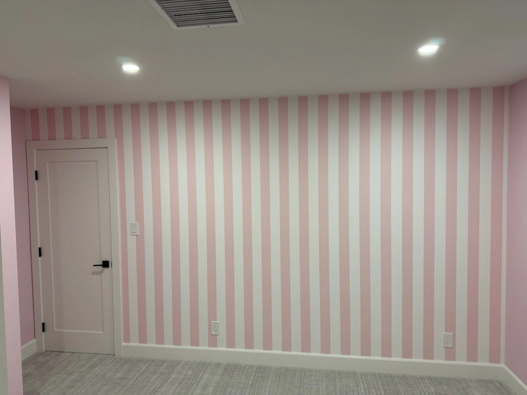 A room with pale pink and light green vertical striped wallpaper
